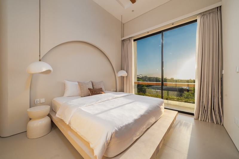 Split-level villa near Balangan: arched headboard and a window onto the trees