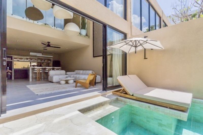 Bingin townhouse: pool and lounger outside the glass-walled living room