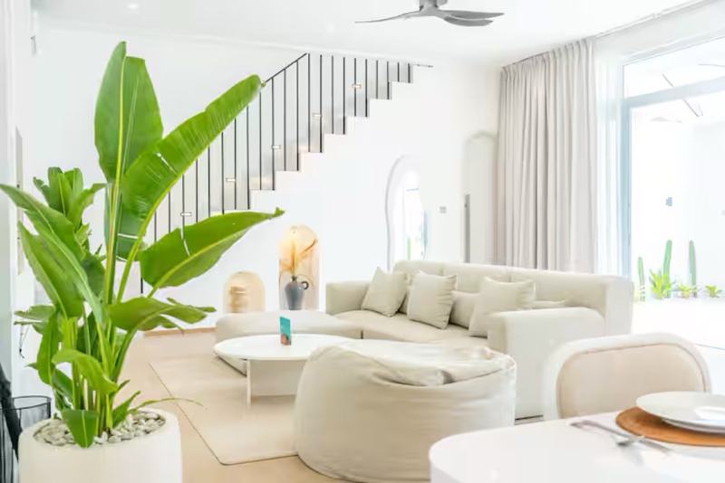 Open-plan villa in Bingin: living room with white sofas and the staircase
