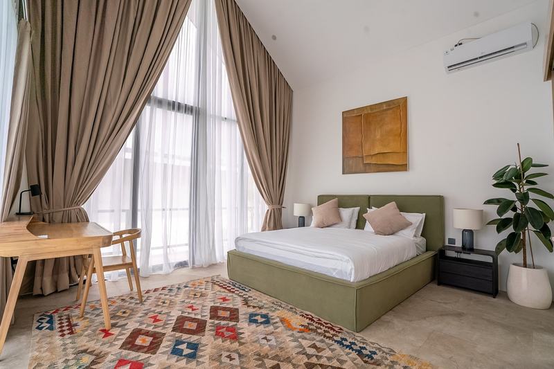 Garden villa in Bingin: bedroom with tall windows and a rug