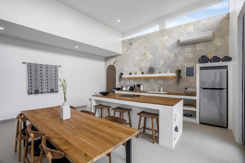 Three-bedroom villa in Bingin: dining area by the kitchen with a stone wall