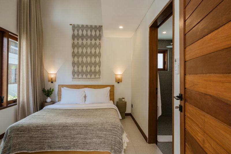 Three-bedroom villa with a wooden deck in Bingin: bedroom with a wooden door to the bathroom