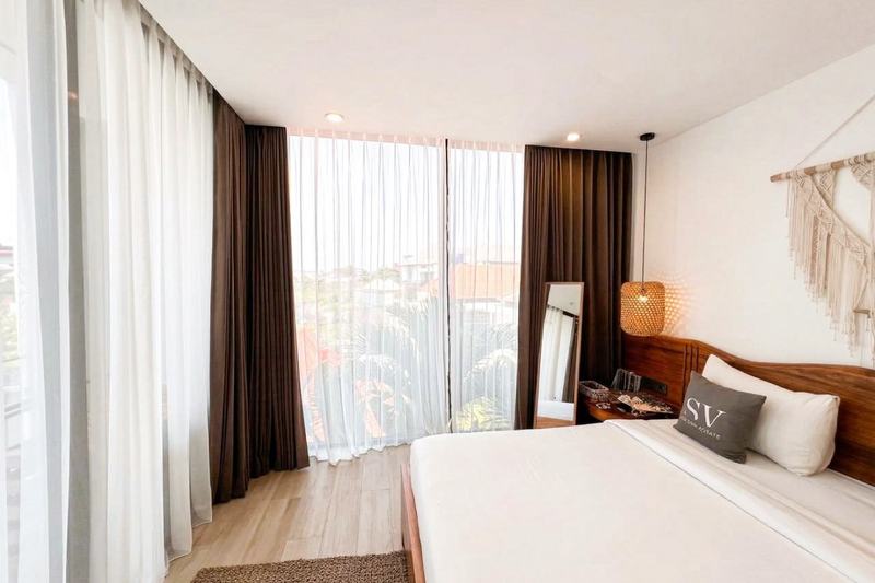 Berawa one-bedroom apartment: bedroom with a wide window over Canggu rooftops