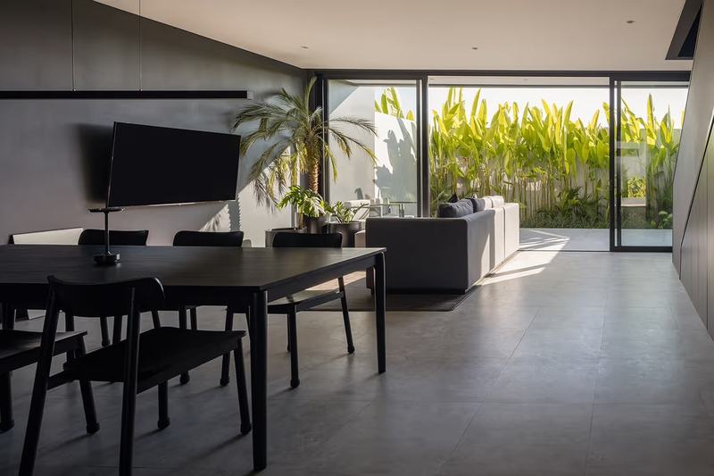 The Grey House: salón comedor con puerta de suelo a techo al patio