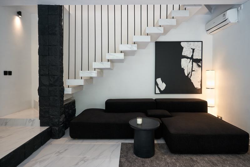 Two-story villa in Ubud: living room with a black sofa below the white staircase