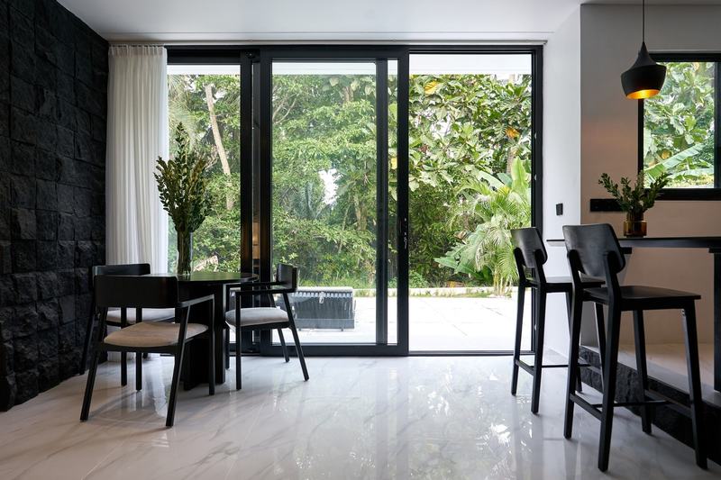 Two-story villa in Ubud: dining table at a full-height window facing the trees