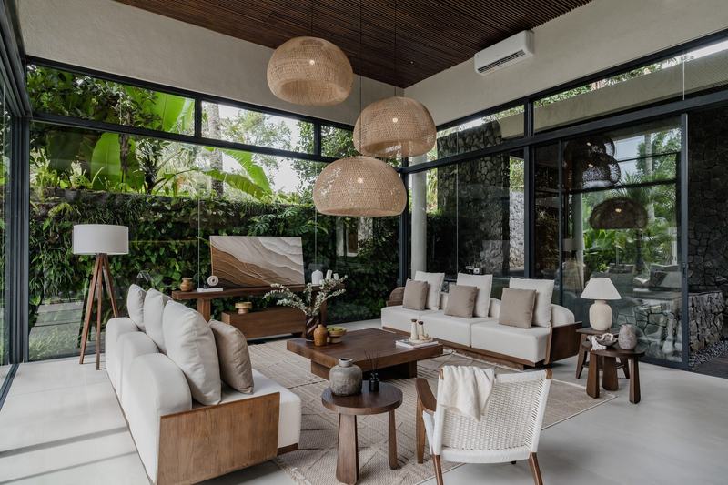 Three-bedroom villa north of Ubud: living room with sofas and woven lamps behind glass
