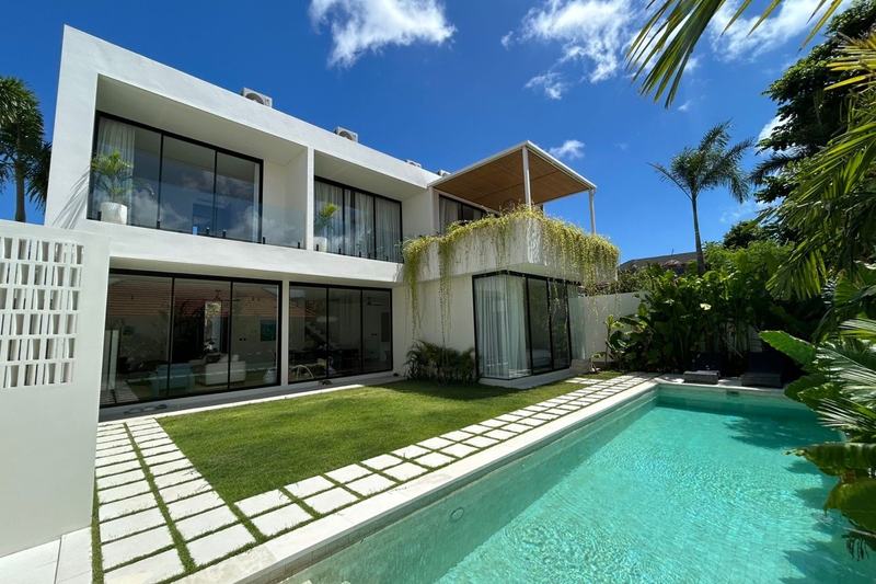 Four-bedroom villa with a study in Uluwatu: two-story house behind a lawn and pool