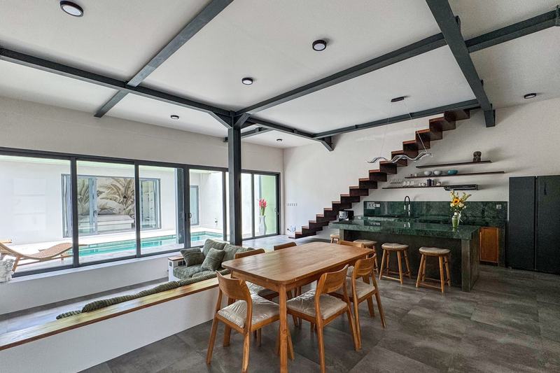 Loft-style villa in Ungasan: dining area and pool behind floor-to-ceiling glass