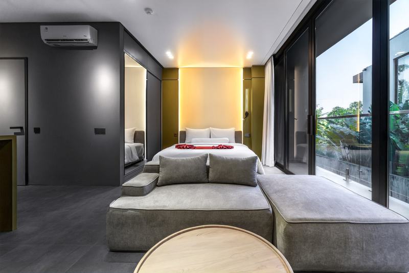 XO Canggu: studio bedroom with a sofa and full-height balcony glass