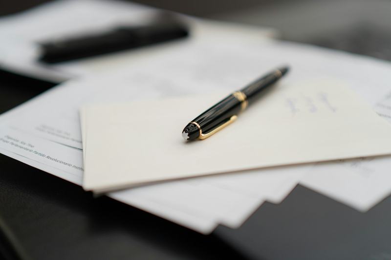 Un stylo-plume posé sur une pile de pages de contrat volantes, sur un bureau sombre