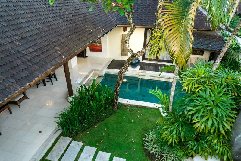 Vue aérienne d'une villa balinaise au toit de tuiles, avec jardin et petite piscine au milieu des palmiers