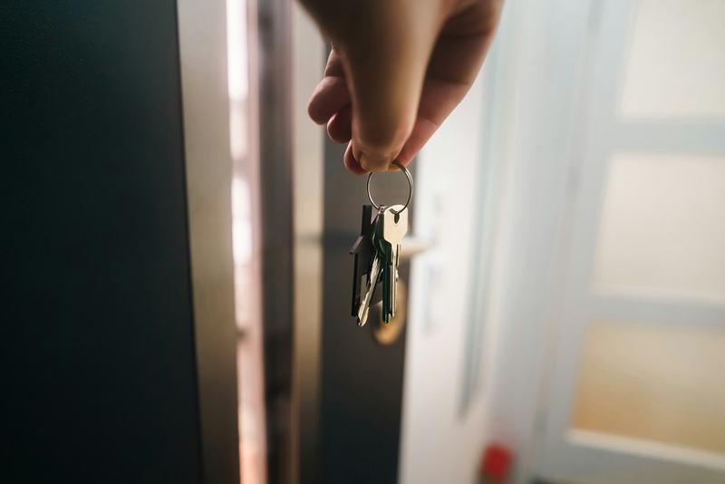 Une main tenant des clés de maison à côté d'une porte ouverte