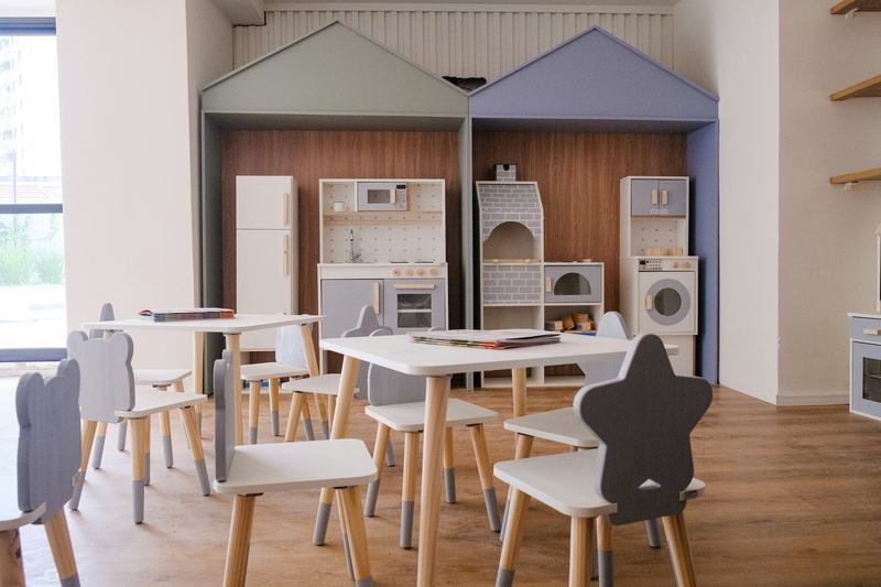 A preschool playroom with small tables, chairs and a toy kitchen