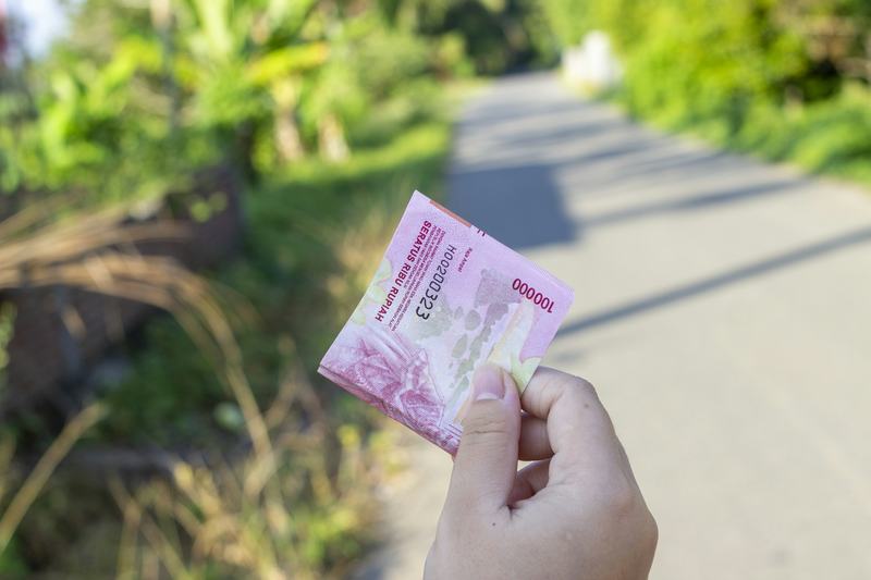 A hand holding Indonesian rupiah banknotes