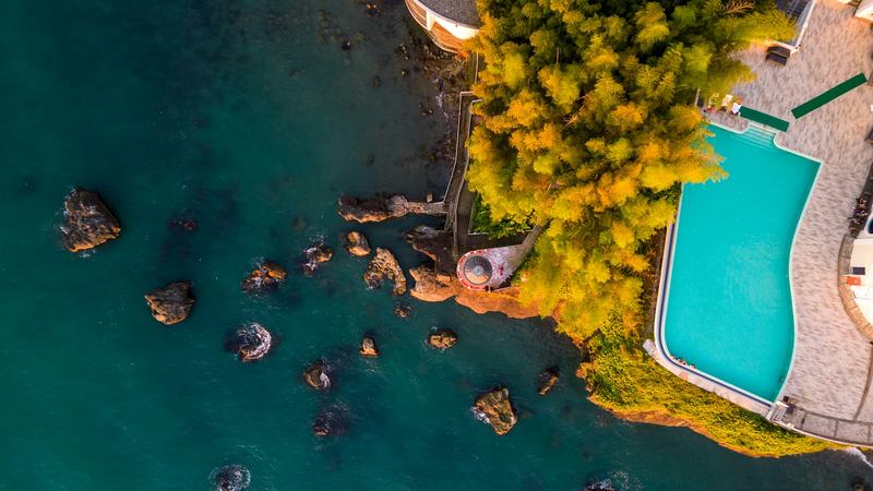 Piscine d'une grande villa vue du ciel, au bord d'un tronçon de côte rocheuse de Bali