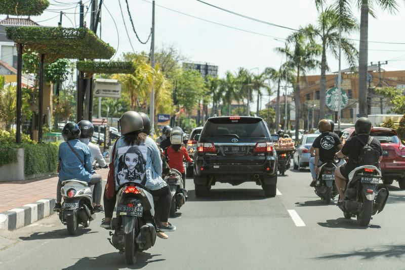 Scooters and cars in daytime traffic on a Bali road