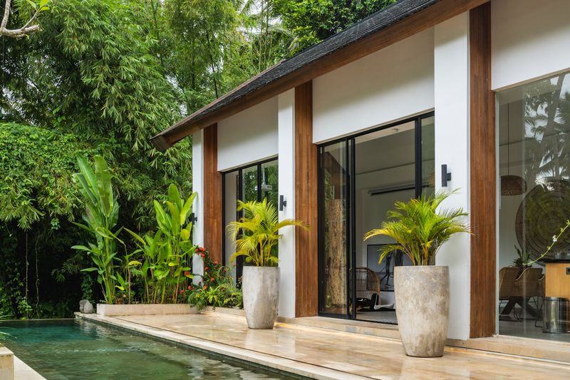 Glass doors of a pool villa opening onto a garden of bamboo and palms